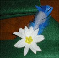 Close-up of green felt hat with blue feather and white Edelweiss flower