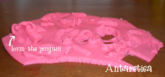 Pink homemade playdough sculpted into an Antarctica scene with a penguin