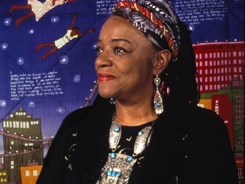 Artist Faith Ringgold in a headwrap and turquoise jewelry before her Tar Beach story quilt